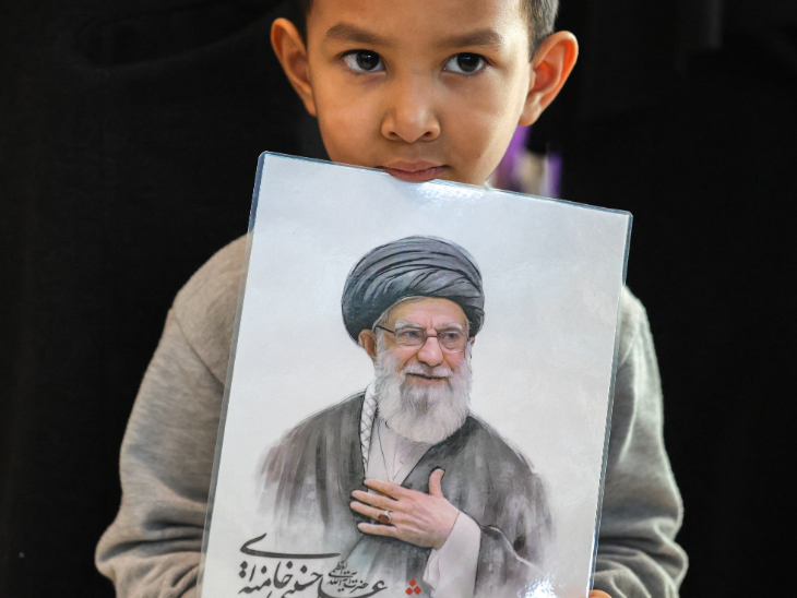 ईरान से वापस लौटे थाई नागरिक सोमवार को बैंकॉक पहुंचे। इनमें 5 साल का मोहम्मद रजावी भी था, जो ईरान के दिवंगत सुप्रीम लीडर अयातुल्ला अली खामेनेई की तस्वीर पकड़े हुए दिखाई दिया।