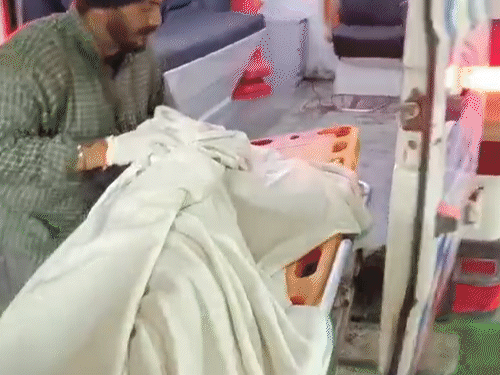 मृतकों के शवों को अस्पताल ले जाते हुए कर्मचारी।