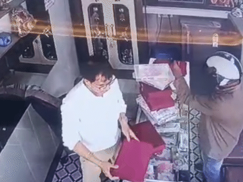 पिस्टल तानकर अलमारी की तरफ इशारा करता बदमाश।