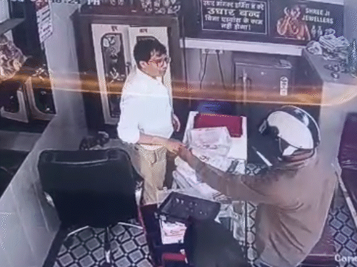 दुकानदार के हाथ से कड़ा उतरवाता बदमाश।