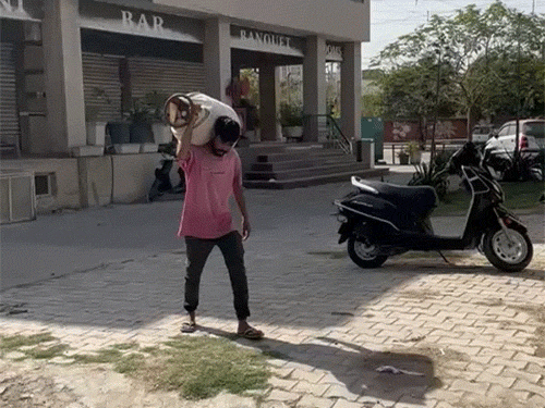 हिसार में कंधे पर सिलेंडर रखकर ले जाता युवक।