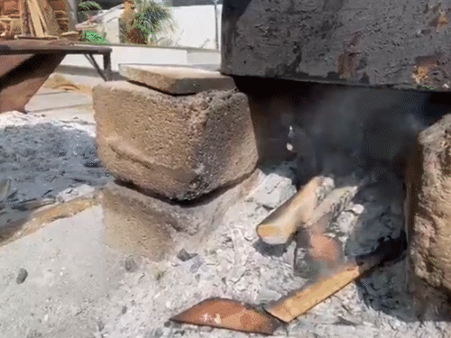 गैस की कमी के कारण बेंगलुरु के राजराजेश्वरी नगर स्थित नम्माओरु कॉफी कट्टा होटल में चूल्हा जलाकर इडली पकाते हुए कर्मचारी।