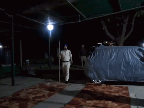 पुलिसकर्मी हाथ में डंडा लेकर खड़ा हुआ।