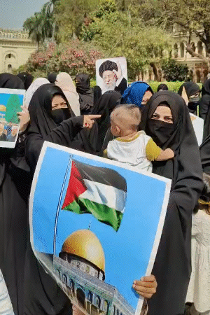 महिलाएं बच्चों को गोद में लेकर पहुंचीं। उनके हाथों में अयातुल्लाह अली खामेनेई के पोस्टर हैं।