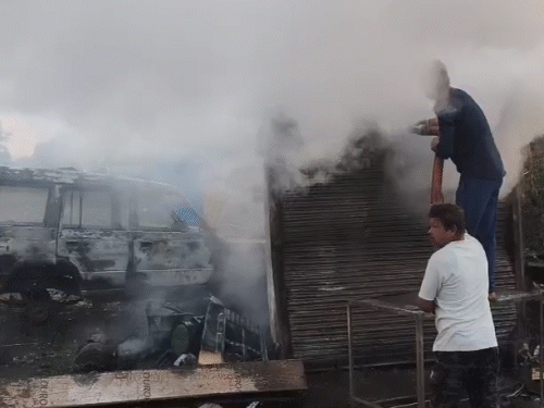 गाड़ी के बाद दुकान में लगी आग बुझाते हुए युवक।