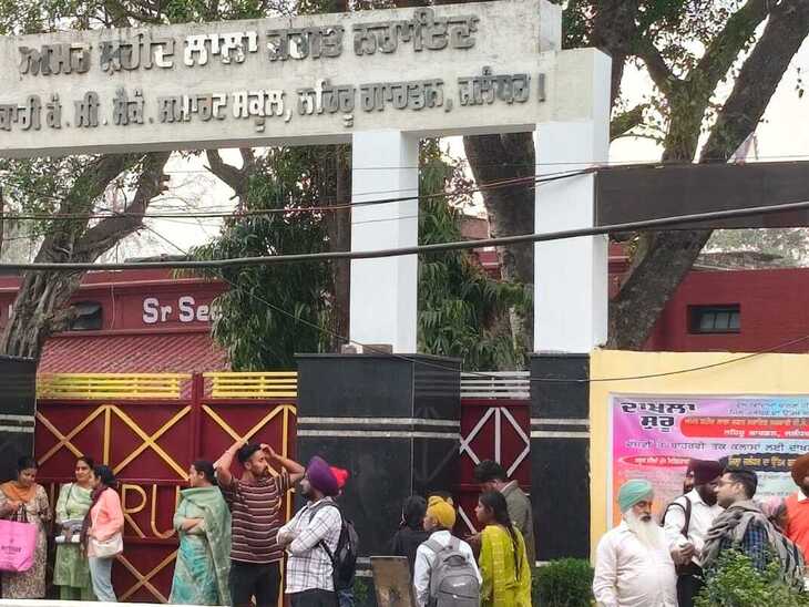 जालंधर में लड़कों के सरकारी स्कूल के बाहर टेट का पेपर दिलाने आए पेरेंट्स गेट के नीचे बारिश से बचते हुए।