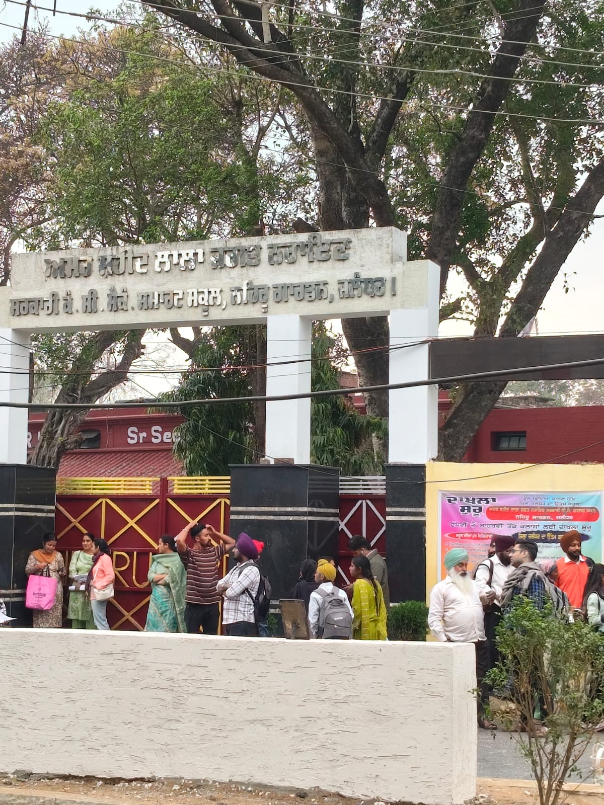 जालंधर के श्री राम चौक में सरकारी स्कूल के बाहर बारिश से बचने के लिए गेट के नीचे खड़े लोग।