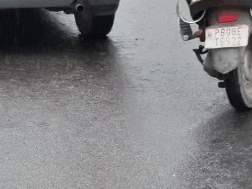 अलास्का चौक के पास बारिश में धीमी रफ्तार में निकलते वाहन।