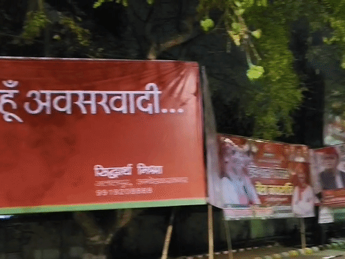 लखनऊ में सपा दफ्तर के बाहर लगे होर्डिंग पर लिखा है- हां, मैं हूं अवसरवादी…।