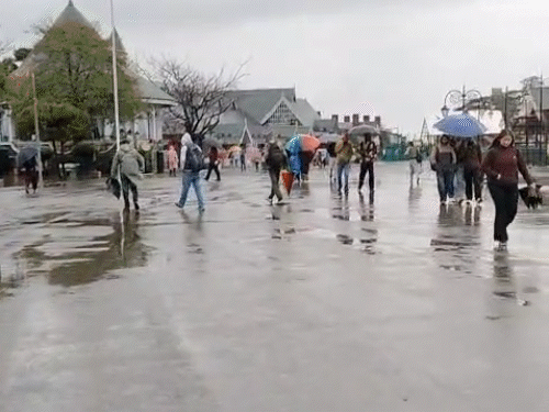 रिजवर पावसात छत्री घेऊन चालणारे पर्यटक आणि स्थानिक लोक.