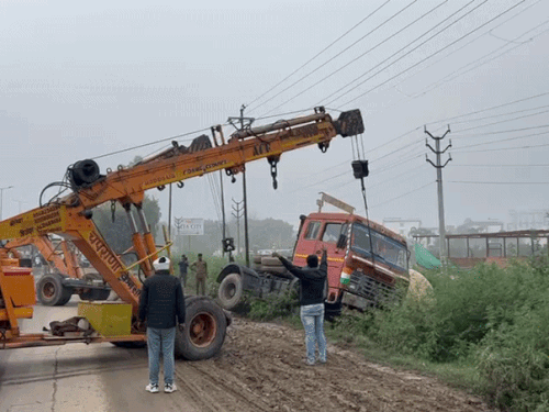 क्रेन से कंटेनर को उठाते कर्मचारी।