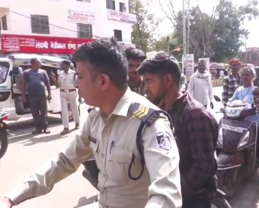 कार चालक को पकड़कर बाइक पर ले जाती पुलिस।