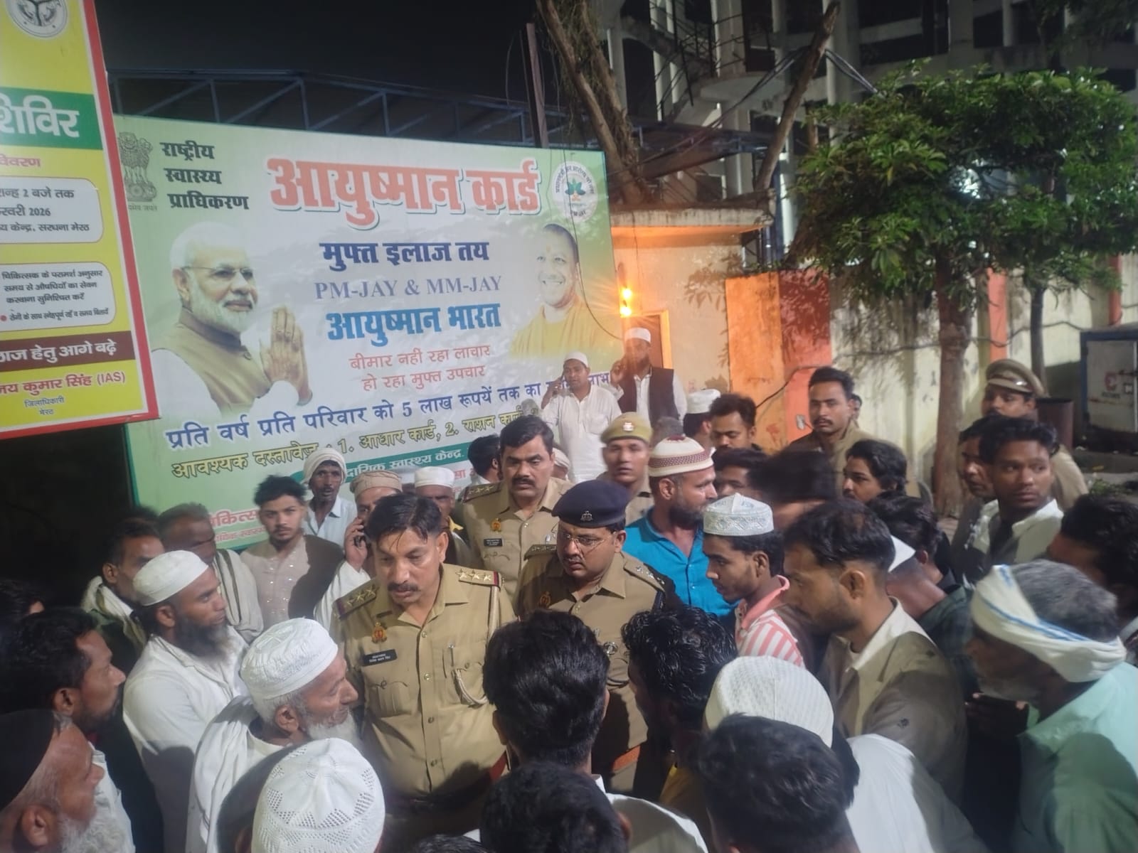 गांव में पुलिस अफसर लोगों को समझा रहे हैं।