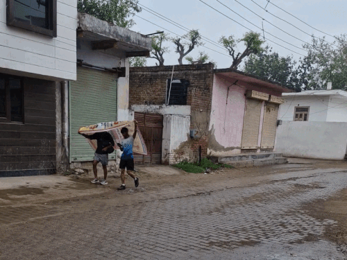 नारनौल में बारिश का बचाव कर चलते हुए युवक