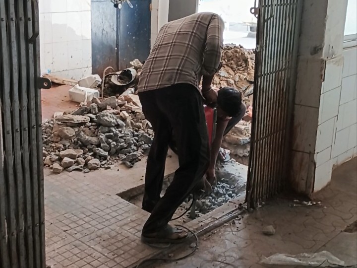 नई पाइपलाइन के लिए फर्श को तोड़ते मजदूर।