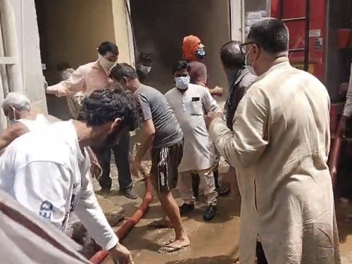 गोदाम से केमिकल के ड्रम निकालते हुए रहवासी।