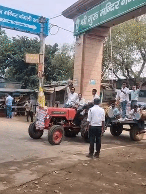 ट्रैक्टरों में लोग ढोल-नगाड़े बजाते हुए चल रहे हैं।