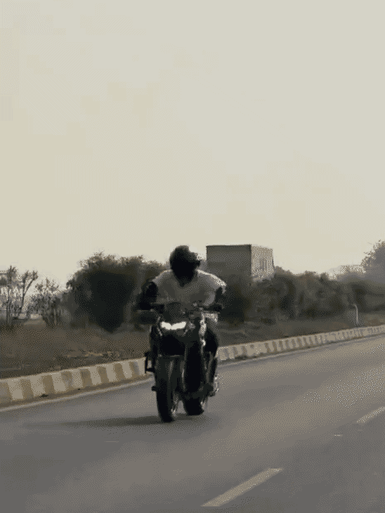 हाइवे पर बाइक से स्टंट करता युवक