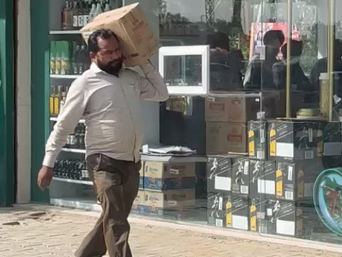 लुधियाना में शराब की पेटी कंधे पर रखकर ले जाते हुए व्यक्ति।