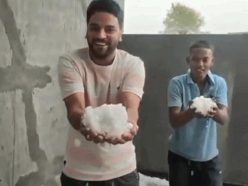 हरियाणा के हिसार में ओले गिरने के बाद बर्फ दिखाते लोग।