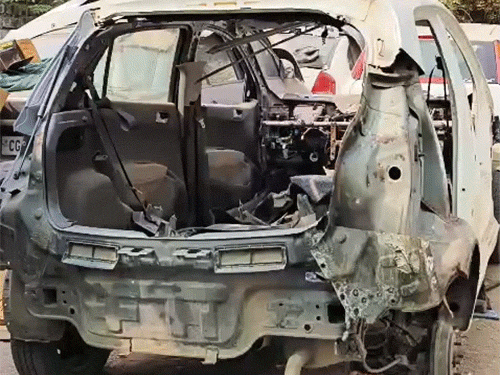 आग में पूरी तरह जलने के बाद यार्ड में खड़ी कार।