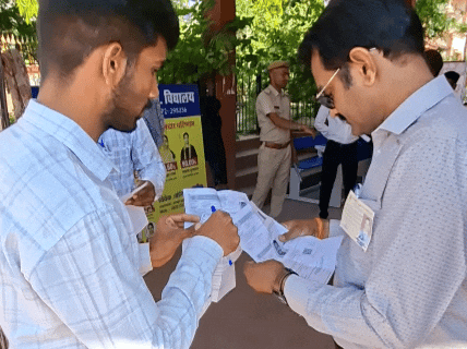 अभ्यर्थी द्वारा लाए गए प्रवेश पत्र की जांच करते हुए सेंटर स्टाफ।