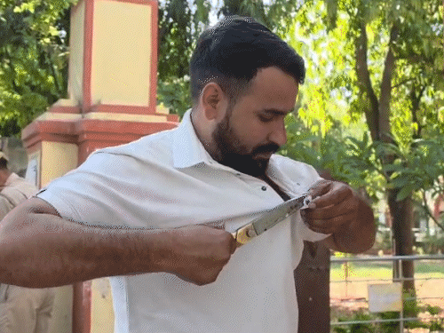 अजमेर के सावित्री स्कूल में कैंची से अपनी शर्ट के मेटल वाले बटन काटता कैंडिडेट।