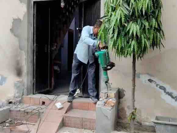 घर के बाहर बनीं सीढ़ियां तोड़ती नगर निगम टीम।