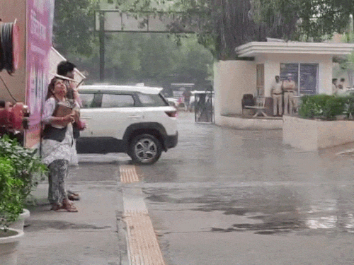 फरीदाबाद में बारिश से बचकर जातीं महिलाएं।