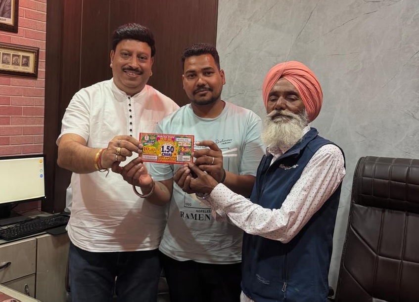 अपना लॉटरी टिकट दिखाते हुए विजेता गुरचरण सिंह (दाएं) और साथ में उसका बेटा मान सिंह (बीच में)।