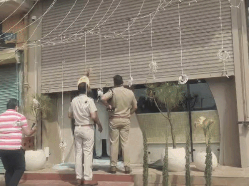 शटर पर लगी गोलियों के निशान को देखती पुलिस।