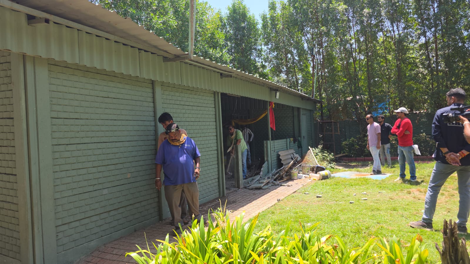 फार्म हाउस के अवैध हिस्से को तोड़ते कर्मचारी।