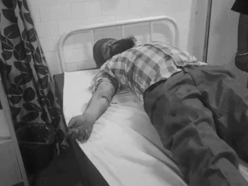 अस्पताल में भर्ती घायल बेटा, जिसके हाथ पर गोली लगी है।