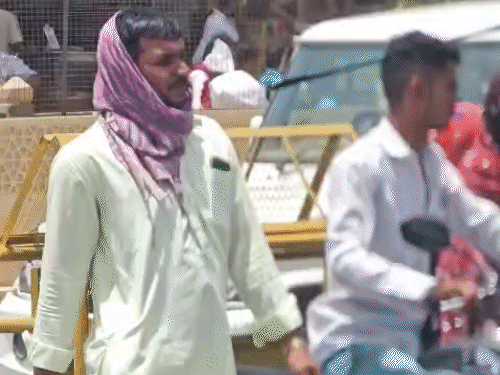 तेज धूप की वजह से लोग कपड़े से सिर ढककर बाहर निकल रहे हैं।