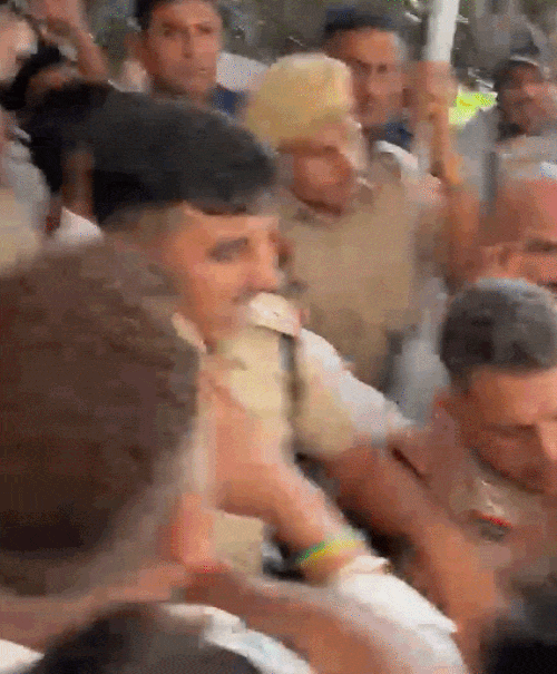 प्रदर्शनकारी छात्रों और जजपा कार्यकर्ताओं को रोकती महिला पुलिसकर्मी।