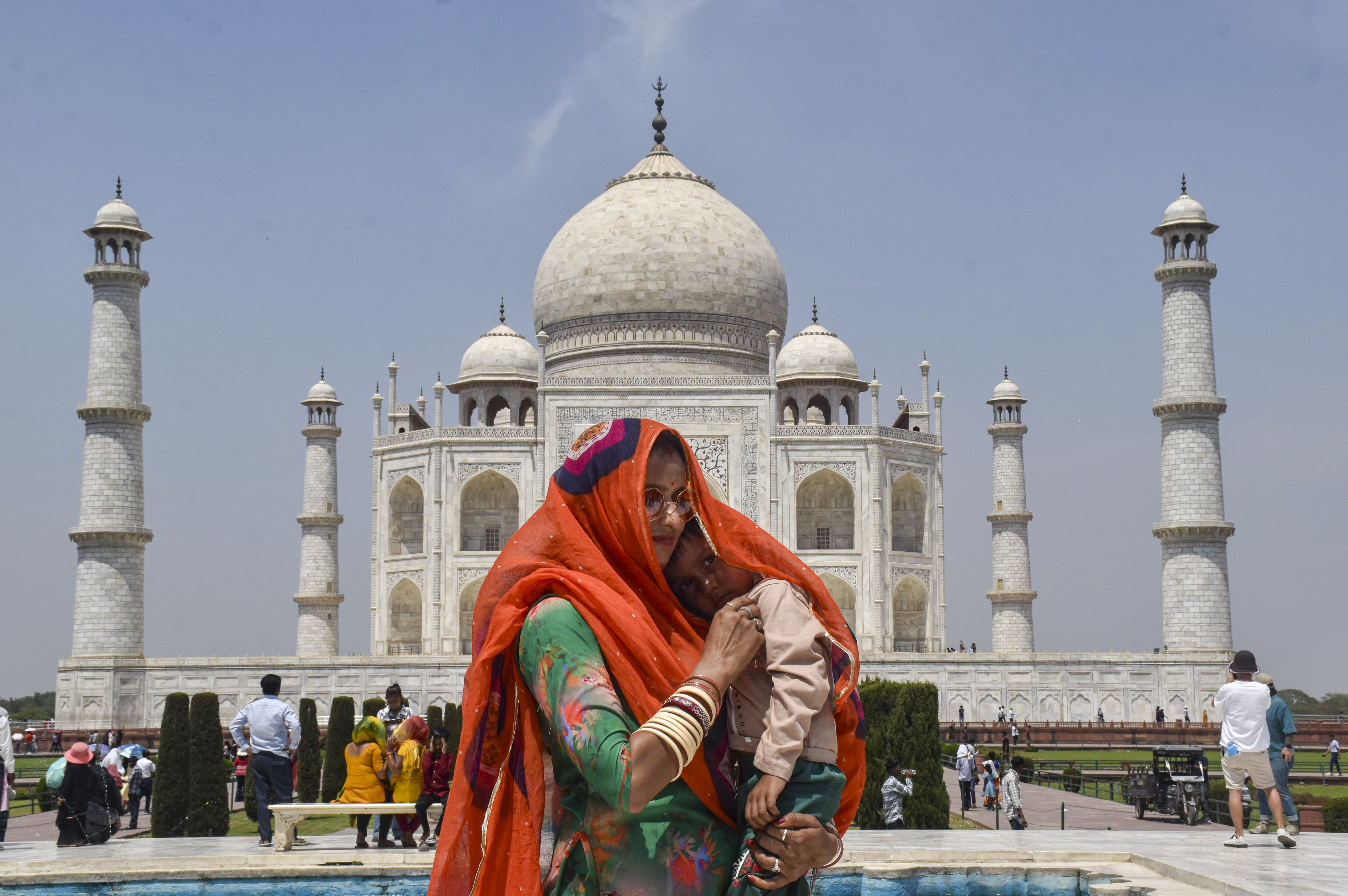 आगरा में ताजमहल देखने पहुंचे पर्यटक तेज गर्मी और धूप से बचने के लिए खुद को कवर कर रहे हैं।