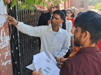 परीक्षा केंद्रों के बाहर रोल नंबर देखते हुए अभ्यर्थी।