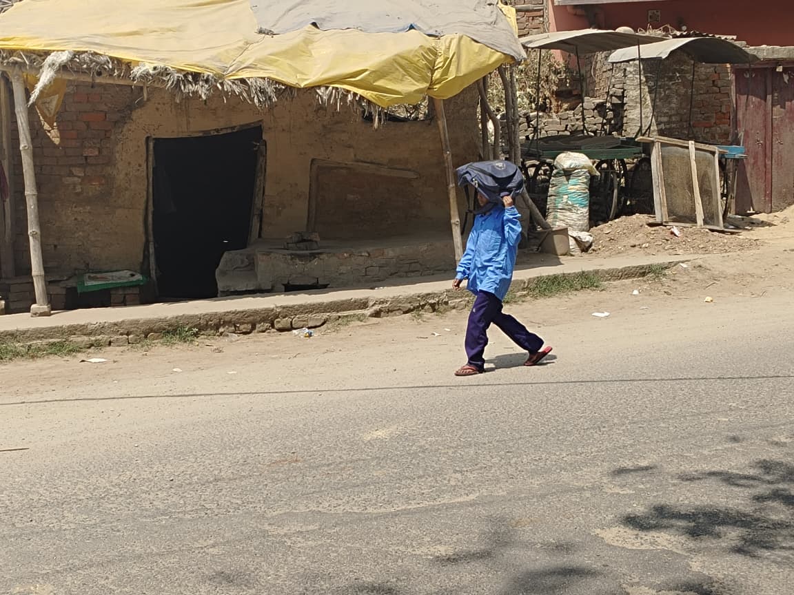 बिहार के बक्सर में तेज धूप से बचने के लिए एक बच्चे ने सिर पर बस्ता रख लिया।