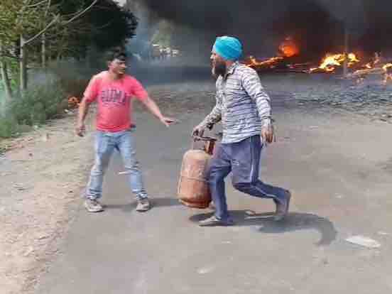 गोदाम में रखे सिलेंडरों को बाहर निकालते लोग।