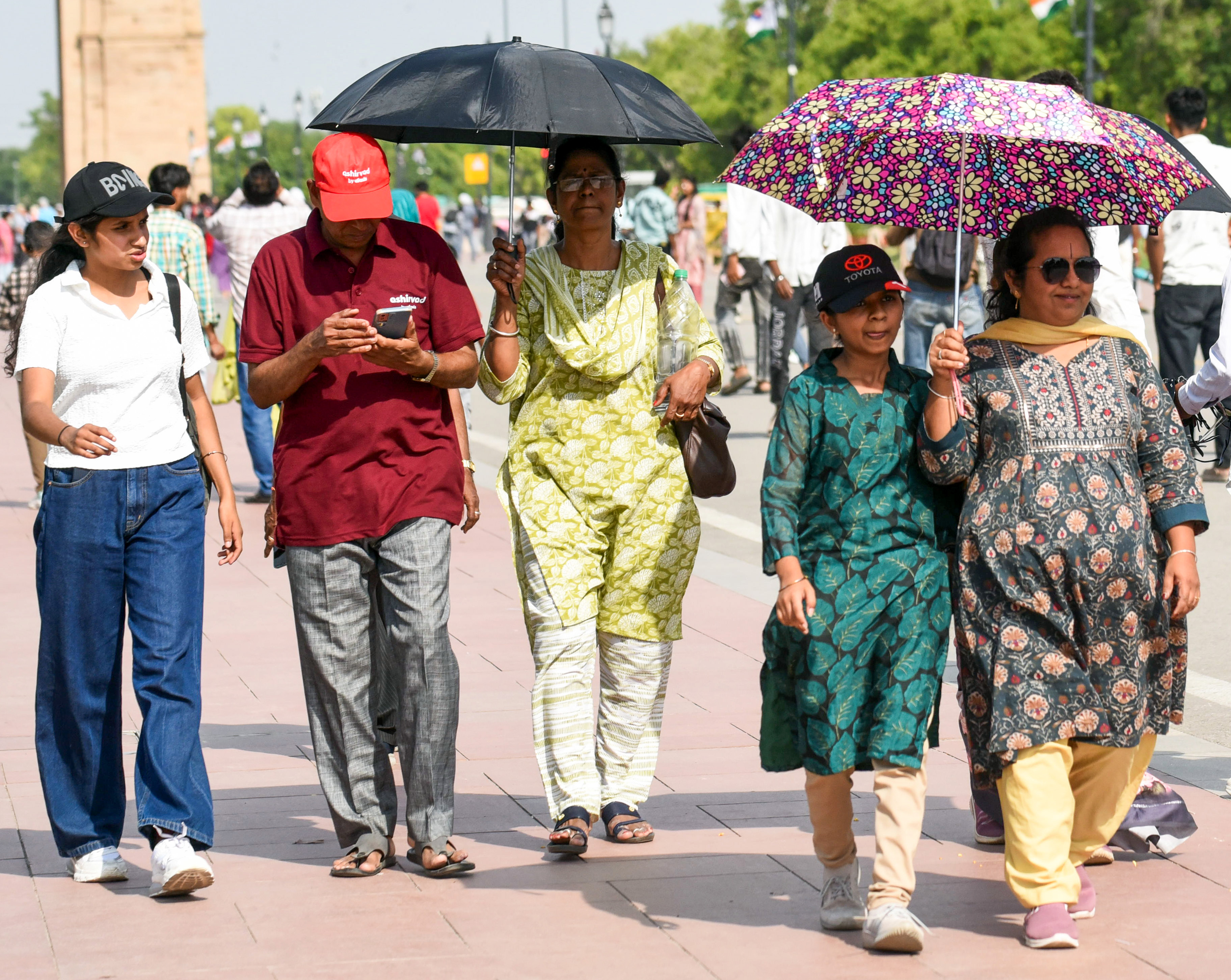 दिल्ली में लोग तेज धूप से बचने के लिए छाता और कैप लगाकर बाहर निकल रहे हैं।