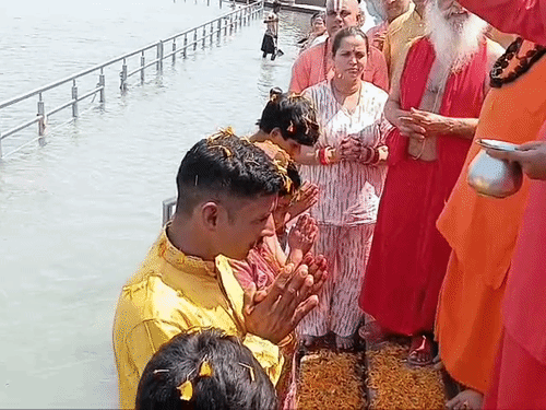 पूरे परिवार पर फूल बरसाते और हर हर महादेव के जयकारे लगाते संत।