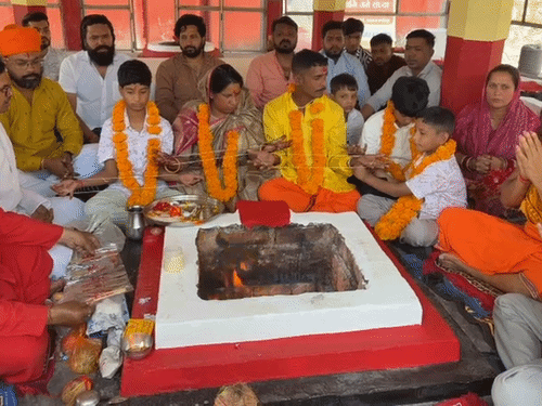 माला पहने और हाथों में जनेऊ लेकर हवन में बैठा शहजाद का परिवार।