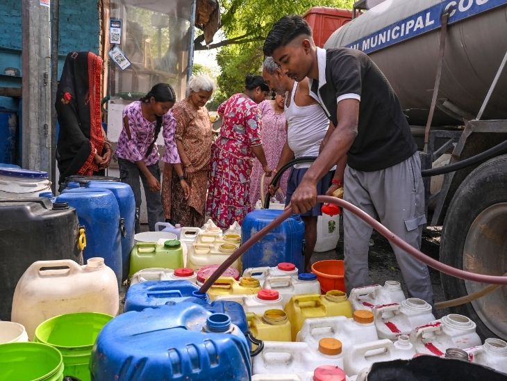 दिल्ली में पानी की किल्लत होने पर टैंकर से पानी भरते लोग।
