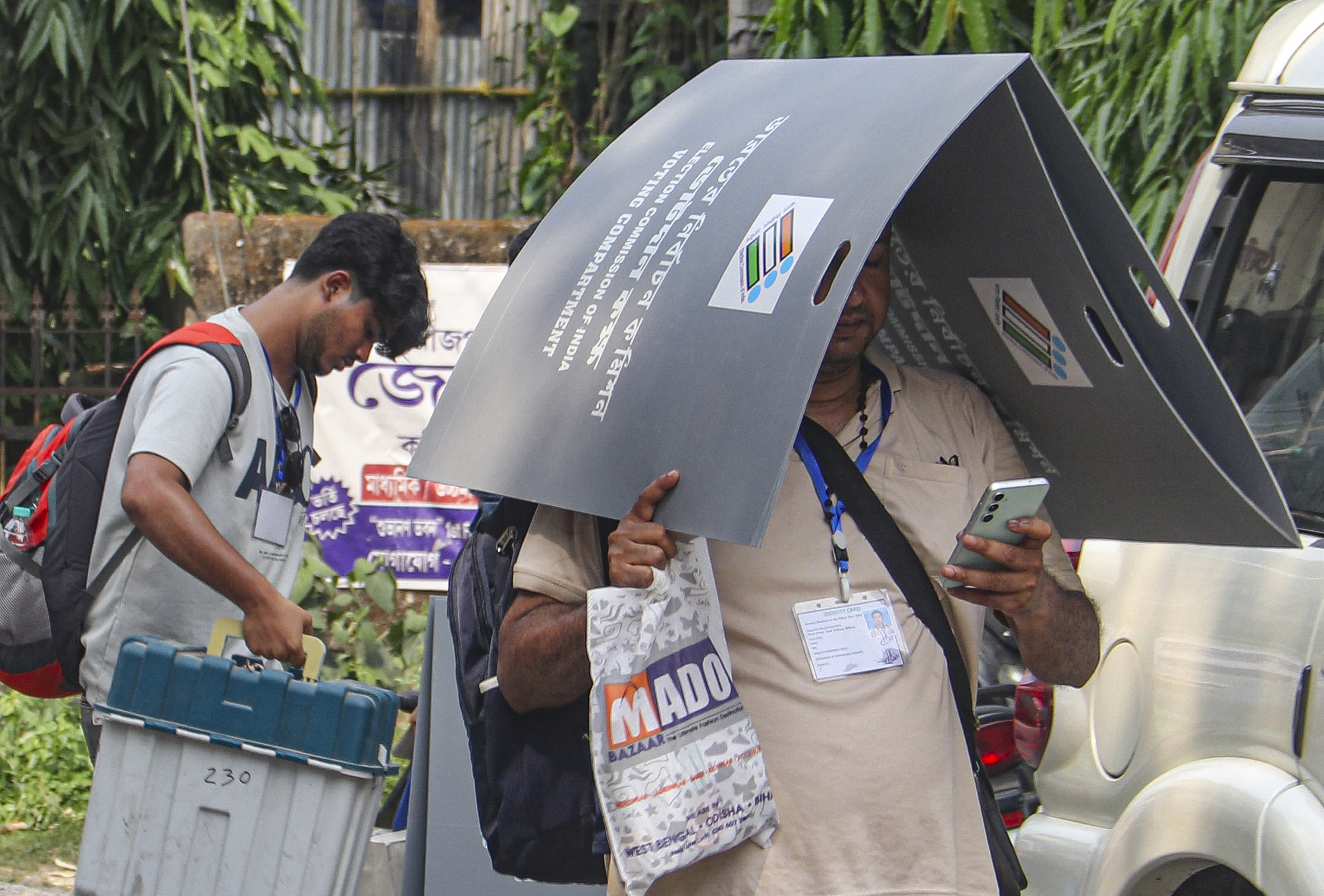 पश्चिम बंगाल के बालुरघाट में चुनाव कर्मचारी ने धूप से बचने के लिए अपना सिर ढंक लिया।
