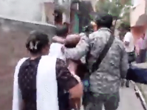 पोलिंग बूथ पर घायल एक शख्स को अस्पताल ले जाते जवान।