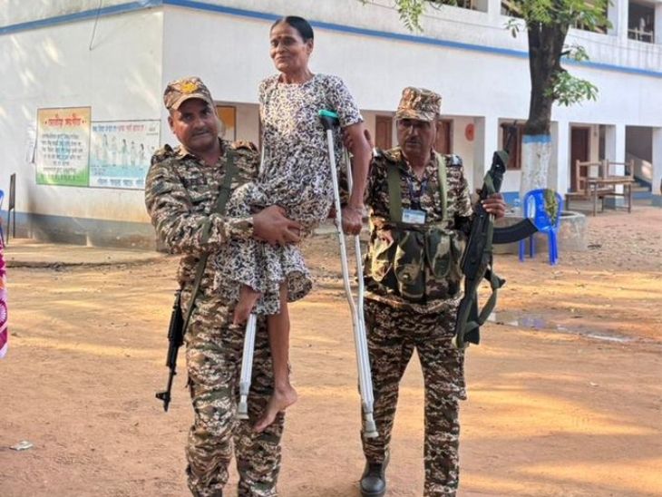 पश्चिम बंगाल के बांकुरा जिले दिव्यांग वोटर की मदद करते हुए सुरक्षाकर्मी।