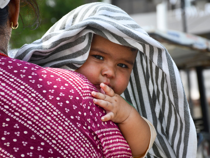 प्रयागराज में भीषण गर्मी के बीच महिला बच्चे को ढककर गर्मी से बचाती नजर आई। यहां गुरुवार को तापमान 40 °C रहा।