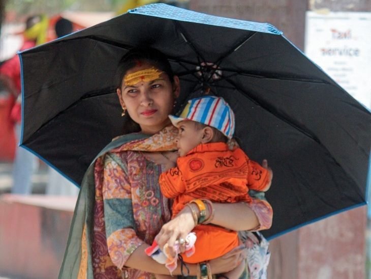 वाराणसी में छाता लगाकर जाती महिला।