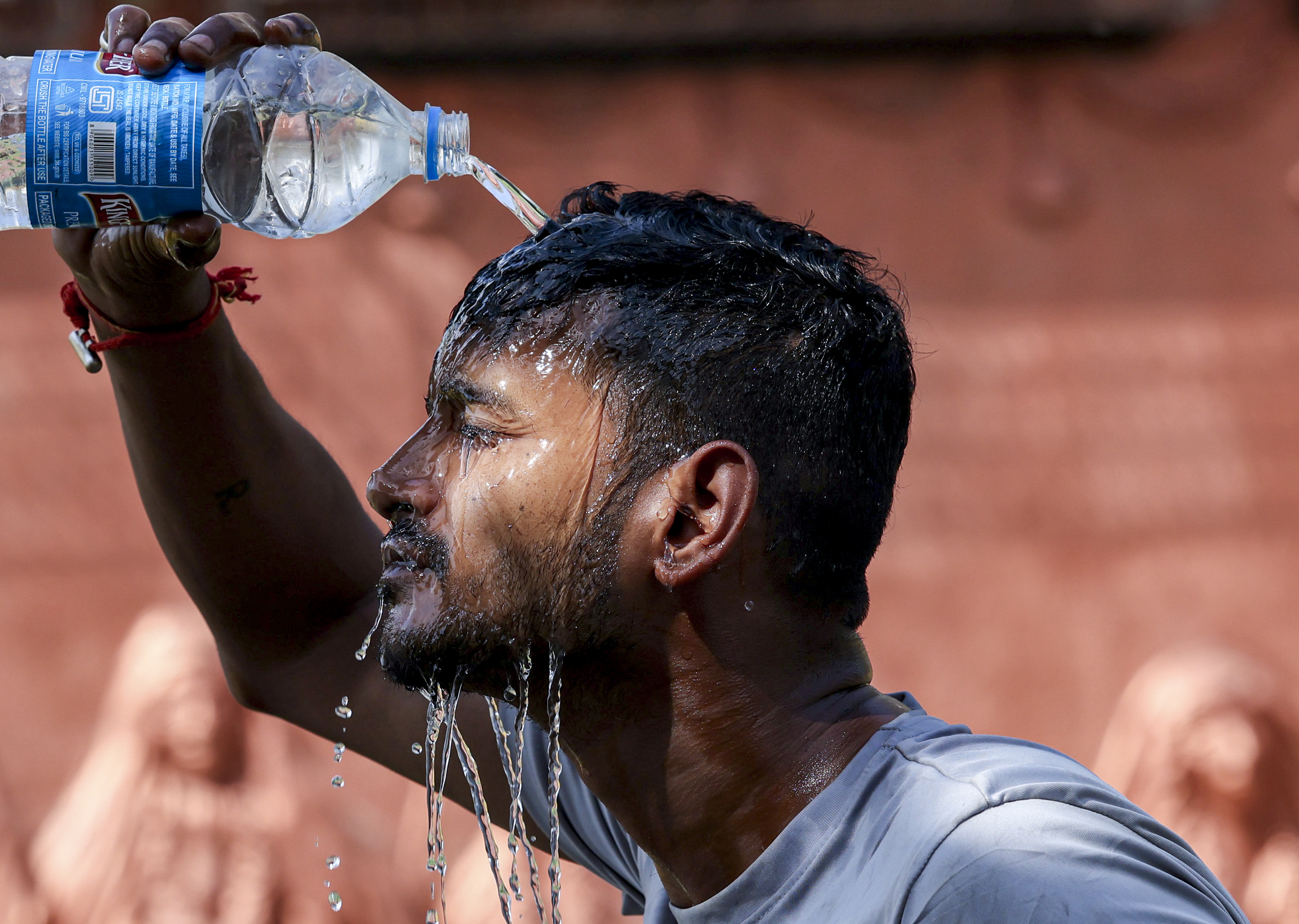 जम्मू में गर्मी से बचने के लिए मुंह पर पानी डालता युवक। यहां पारा 39.5°C रहा।