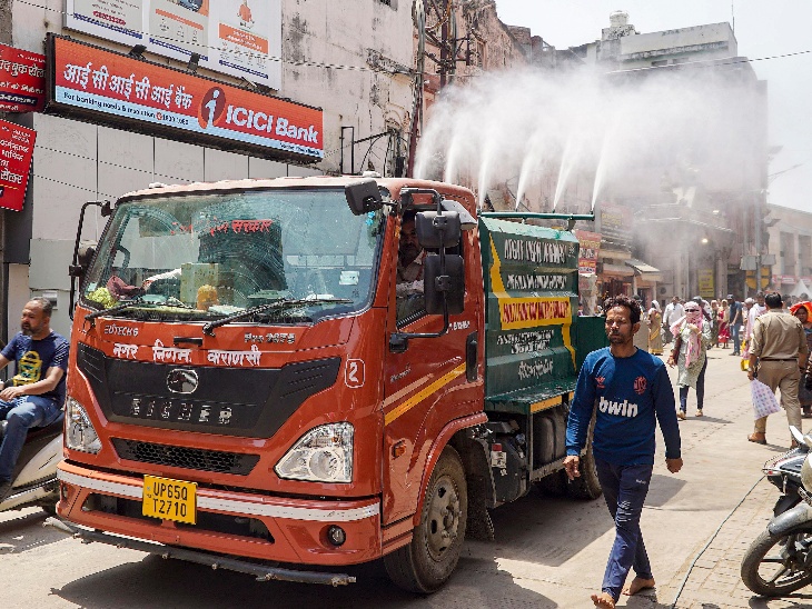 उत्तर प्रदेश के वाराणसी में शुक्रवार को लू के प्रकोप के बीच राहत देने के लिए नगर निगम का एक टैंकर सड़क पर पानी का छिड़काव करता दिखाई दिया।